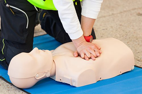 Female instructor showing CPR on training doll.